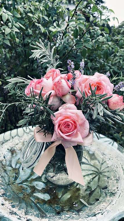 Pink garden roses and rosemary in a glass jar